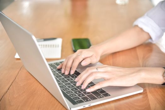 Young businesswoman using laptop on her desk at the workplace, closeup