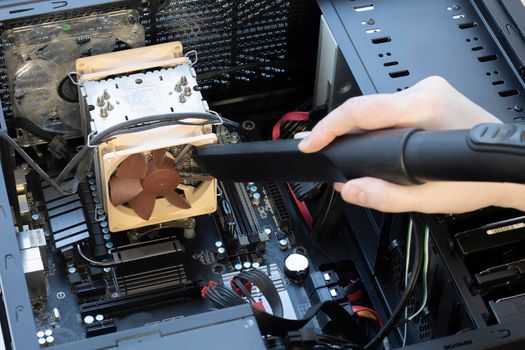 a very dirty computer fan inside the computer being cleaned with a vacuum cleaner close-up.