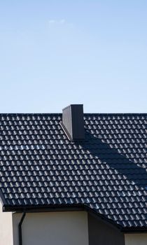 Brown corrugated metal profile roof installed on a modern house. The roof of corrugated sheet. Roofing of metal profile wavy shape. Modern roof made of metal. Metal roofing