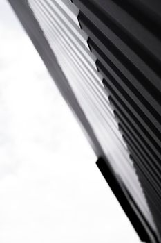 Black and white corrugated iron sheet used as a facade of a warehouse or factory. Texture of a seamless corrugated zinc sheet metal aluminum facade. Architecture. Metal texture