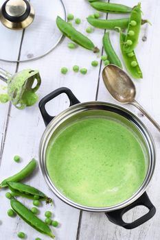 Saucepan of freshly cooked soup of mashed green peas and cream on the table.