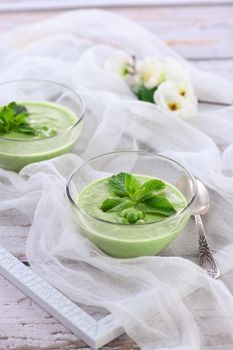 Chilled green pea puree soup with tender milk cream and refreshing mint