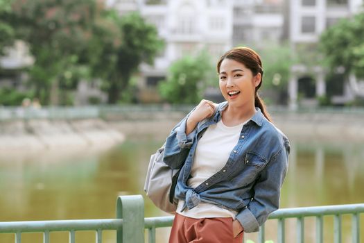 Portrait of a smiling young girl with backpack standing outdoors 