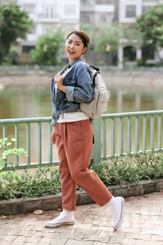 Portrait of young stylish hipster woman walking on the street, wearing trendy outfit, travel with backpack.