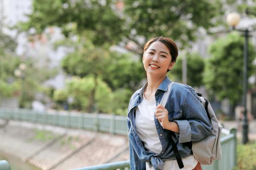 Portrait of young stylish woman walking on the street, wearing cute trendy outfit, smiling enjoy her weekends, travel with backpack