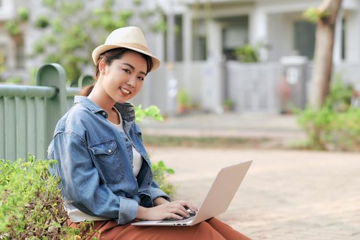 Concentrated at work. Confident young asian woman wearing casual and working on laptop for to do remote learning from anywhere while sitting on the city outdoors.