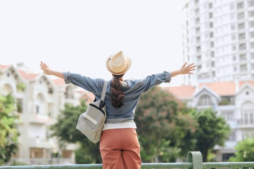 Happy young female traveler in the big city. Back or rear view of young woman and backpack