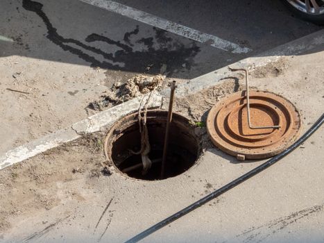 Open sewer hatch on a street. Repair of sewage, underground utilities, water supply system, water pipe accident