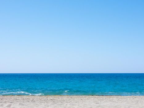 Summer mediterranean beach background. Horizon with calm sea, clear sky and grey sand