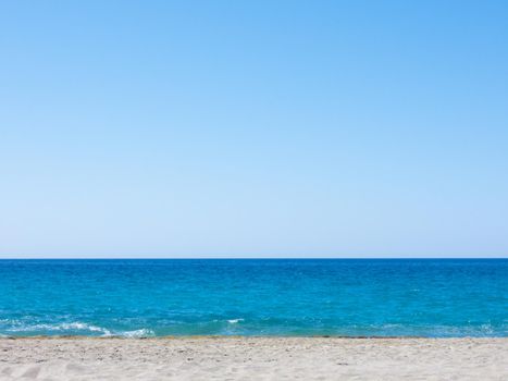 Summer mediterranean beach background. Horizon with calm sea, clear sky and grey sand