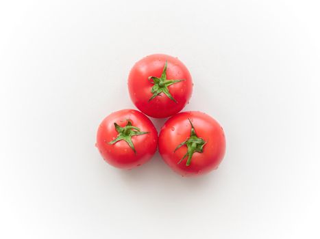Three ripe tomatoes on a light gray ceramic surface. Top view. Not isolated