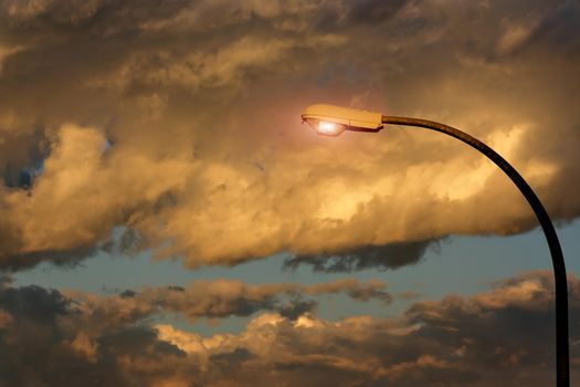Street lamp lit with storm clouds in the background.