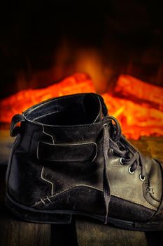 Casual gray leather shoe for men on wooden board with fireplace in the background. Dark mood style. Horizontal image.