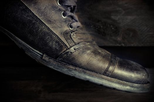 Detail of gray leather casual shoe for man on wooden board. Dark mood style. Horizontal image.