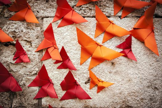 Group of birds Origami orange and red on a wall.