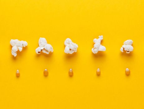 Corn grains and popcorn in a row on yellow background. Concept of evolution and growth. Horizontal image. Top view.