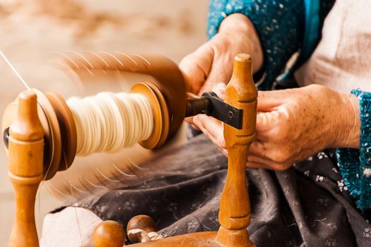 Oldster spinning cotton of traditional form on a craftsmen's market.
