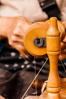 Oldster spinning cotton of traditional form on a craftsmen's market.