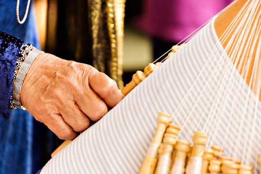 Craftswoman working with bobbin lace in a craft market.