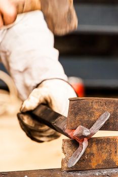 Blacksmith working a metal piece with the hammer on a craftsmen's market.