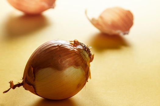 Onion with backlight with onion skins at the bottom on yellow surface. Healthy life concept. Horizontal image.