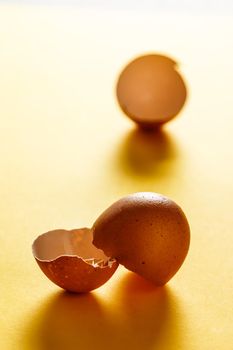 Egg shells on yellow surface with more shells in the background. View in the foreground. Food for a healthy life. Vertical image.