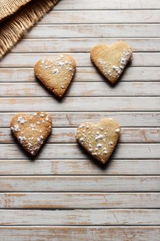 Delicious home-made heart-shaped cookies sprinkled with icing sugar in a wooden board. Horizontal image seen from above. 