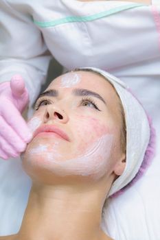 A young woman is wiped off traces of blood from a plasma injection on her face. Plasmolifting. Apply cream.