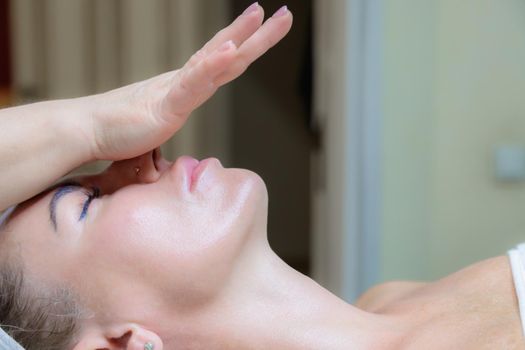 The girl is given a face and neck massage in a beauty salon. Enjoy the procedure