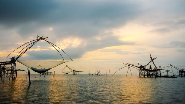 Beautiful nature landscape of Songkhla Lake at sunrise and fisherman are using bamboo and net as native fishing tool to catch fish rural lifestyle at Pakpra canal, Baan Pak Pra, Phatthalung, Thailand