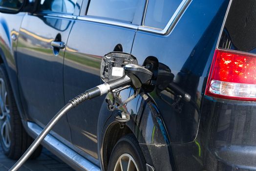 refilling the black car with a diesel with gas pump.