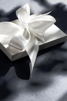 Anniversary celebration, shop sale promotion and luxe surprise concept - Luxury holiday white gift box with silk ribbon and bow on black background, luxe wedding or birthday present