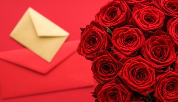 Holiday gift, flowers flatlay and happy relationship concept - Love letter and flower delivery service on Valentines Day, luxury bouquet of red roses and card envelopes on red background