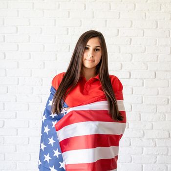 Independence day of the USA. Happy July 4th. Young smiling woman with national flag of the USA.