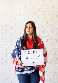 Independence day of the USA. Happy July 4th. Woman with american flag holding lightbox with words Happy 4 July