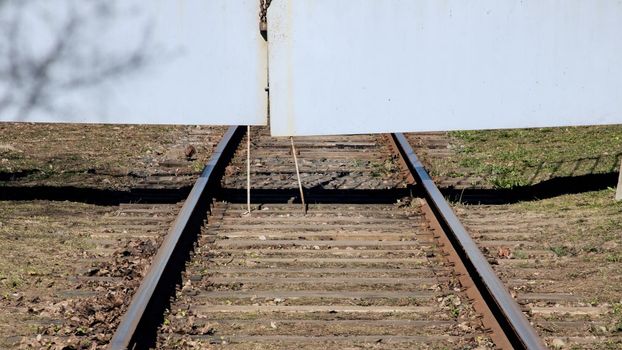 Railway rests against the meallic gate close up, green grass