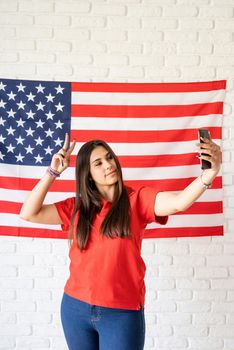 Independence day of the USA. Happy July 4th. Beautiful woman taking a selfie on the USA flag background