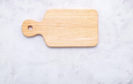 Empty vintage wooden cutting board set up on white concrete background with copy space.