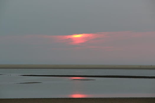 Sunset at a beach at the North Sea with reflexion on the water