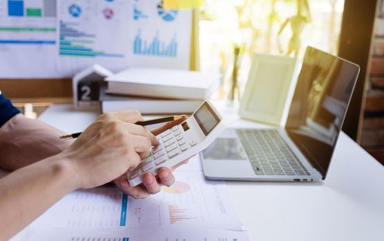 Businessman or Man entrepreneur holding pencil and using a calculator to calculate financial expense at the home office. Business accounting concepts.