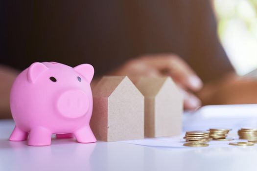 The personal saving financial concept for own a house. Piggybank and house model and banker or office worker calculate savings money.