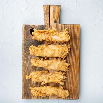 Crispy chicken tenders cuts on white background, top view.