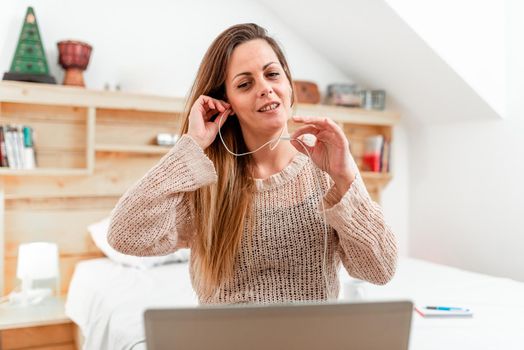 Casual Lady Having Call From Her Room Using A Computer With Headset, Business Woman Having A Vedio Conference Meeting Through A Laptop And Wired Headphones From Bedroom.