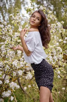 Tender young elegant beautiful girl in the garden near the blossoming apple tree. Youth concept