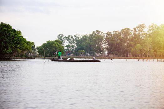 Native fisherman are standing prepare the nets to catch fish, on a small wooden boat under the morning light, Lifestyle in the countryside at Pakpra canal, Songkhla Lake, Phatthalung, Thailand