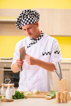 Young professional cook preparing salad at kitchen