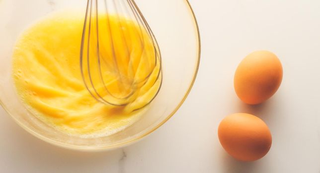 Cooking, meal and diet concept - Making of mixing eggs in bowl on marble table as homemade food flat lay, top view food brand photography flatlay and recipe for cooking blog, menu or cookbook design