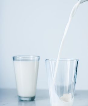 Dairy, healthy nutrition and breakfast concept - World Milk Day, pouring into glass on marble table