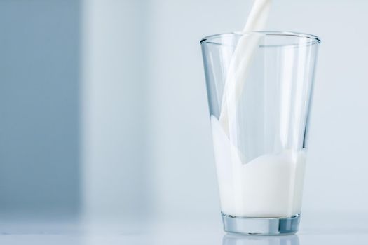 Dairy, healthy nutrition and breakfast concept - World Milk Day, pouring into glass on marble table