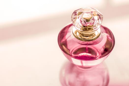 Perfumery, spa and branding concept - Pink perfume bottle on glossy background, sweet floral scent, glamour fragrance and eau de parfum as holiday gift and luxury beauty cosmetics brand design